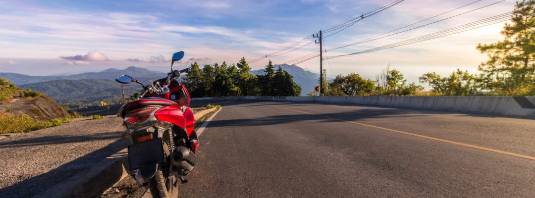 Motorcycle, serpentine road, mountains on background and blue sky on sunset. Active lifestyle and vacation concept.